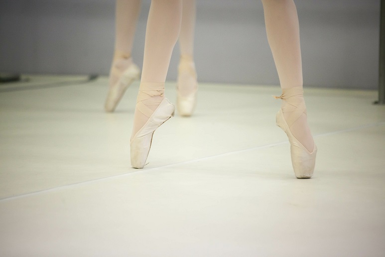 Pernas de bailarina em sapatilhas bege ficando nas pontas dos pé