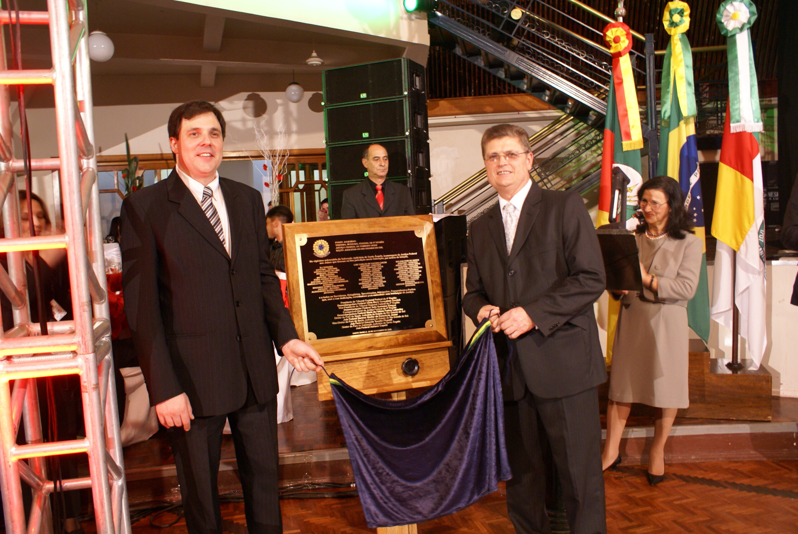 a foto mostra os dois juízes retirando o pano que cobria a placa comemorativa