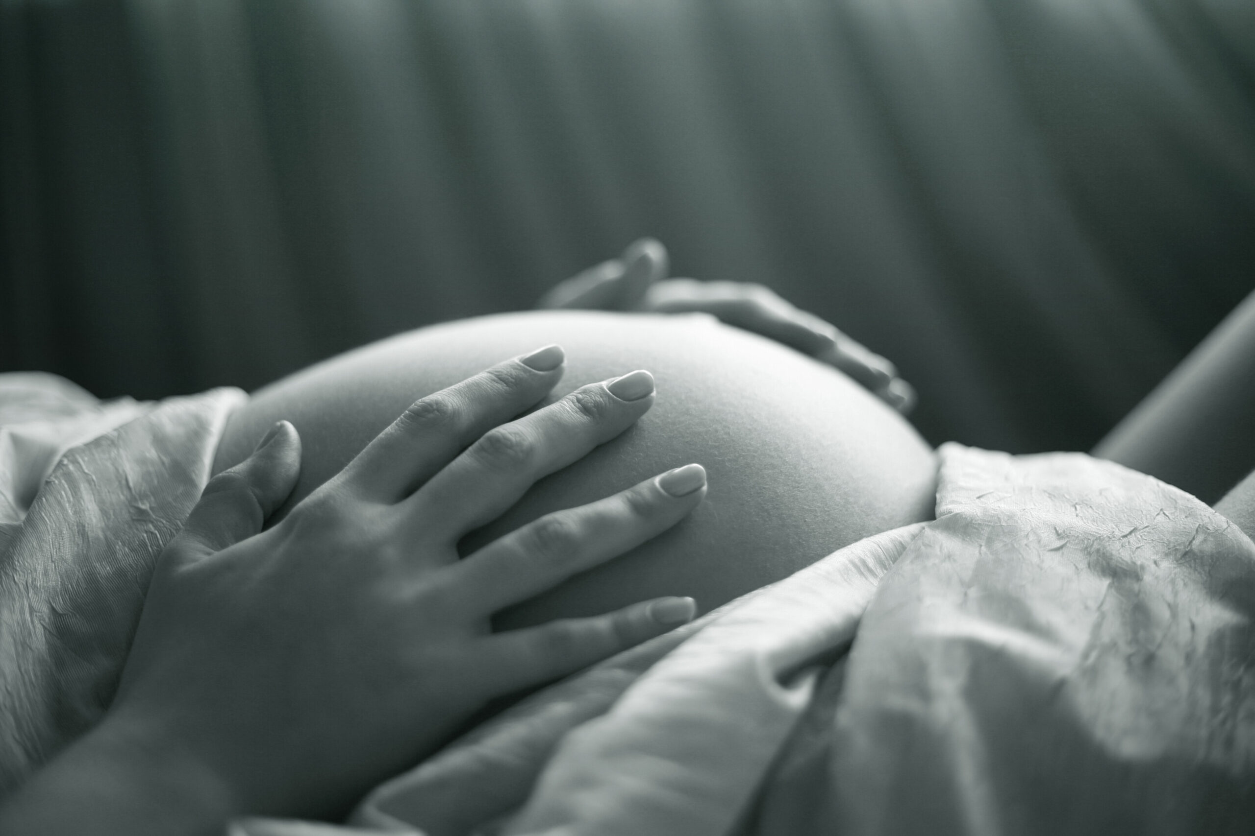 a foto mostra a barriga de uma gestante, que está com as duas mãos nela