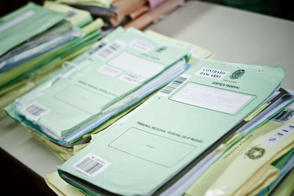 Processos da justiça federal sobre uma mesa, todos com capa verde.