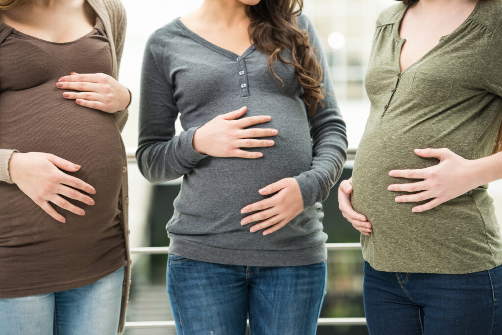 a foto mostra três mulheres grávidas com as mãos na barriga, mas não aparece os rostos