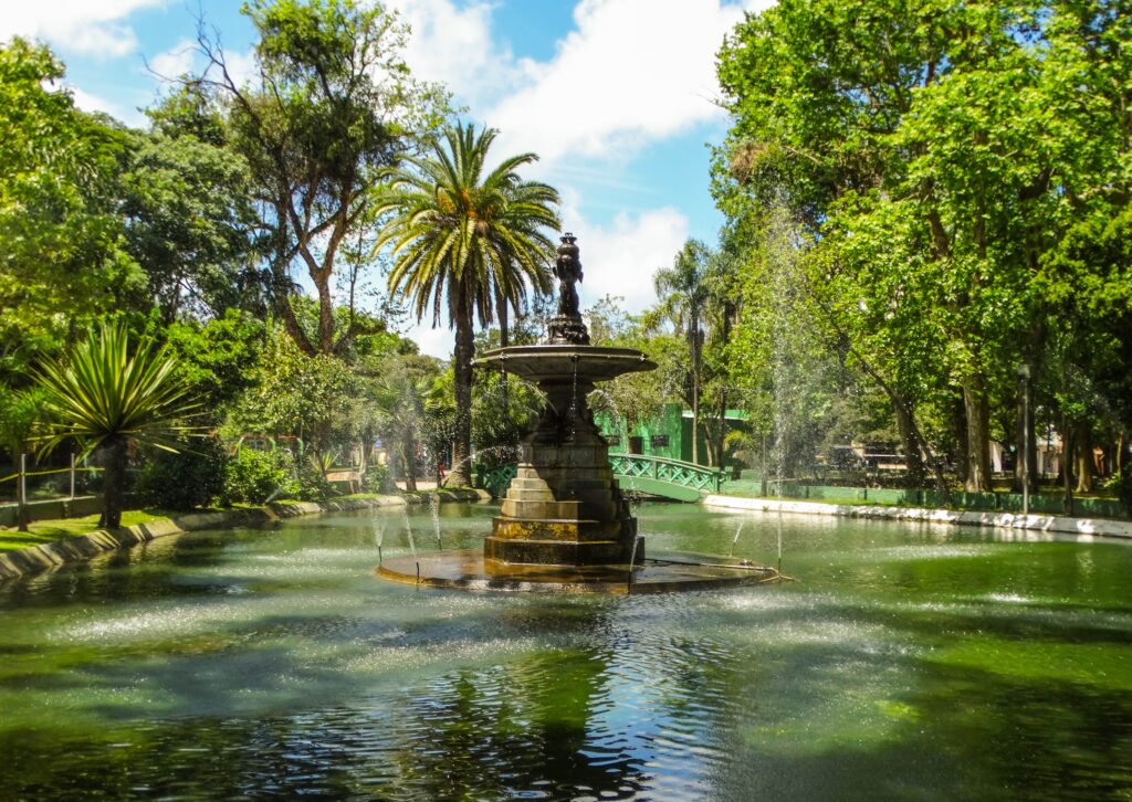 Praça tamandaré, Chafariz dos Anjos - foto de Mauren Da Silva Rodrigues . Chafariz no meio de um lago. Ao fundo uma ponte. Aos redor muitas árvores .
