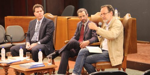 3 debatedores sentados: Dr. Ronald Kruger Rödor, Dr. Roberto Schaan Ferreira e Luís Augusto Fischer - este último com o microfone na mão.